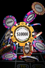 Casino chips fall onto a roulette table. The $10,000 chip is featured. 
