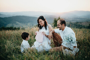 Happy parents telling their son about new coming baby sister