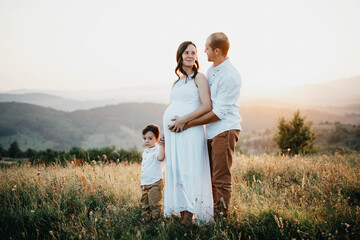 Pregnant woman holding his son and husband hands at sunset