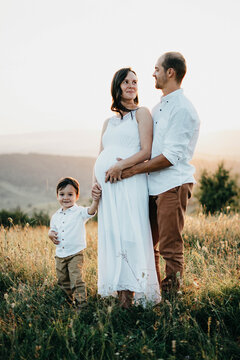Happy pregnant woman holding his son and husband hands