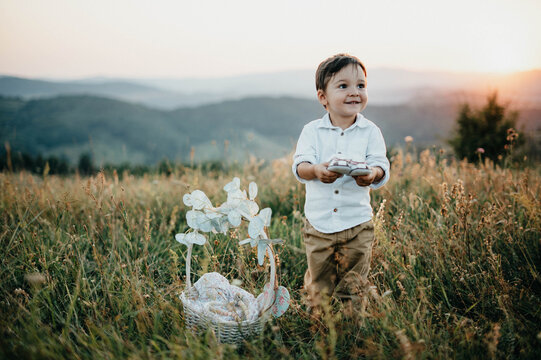 Young boy playing  with his sister's shoes in the nature