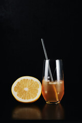 Grapefruit cocktail and half a grapefruit on a black background.
