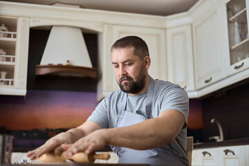A man is rolling out dough in the kitchen
