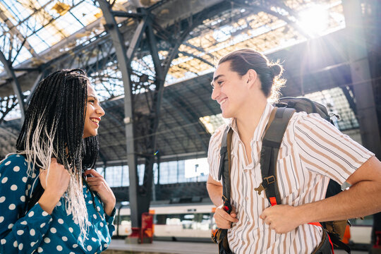 Cheerful diverse couple on railroad station