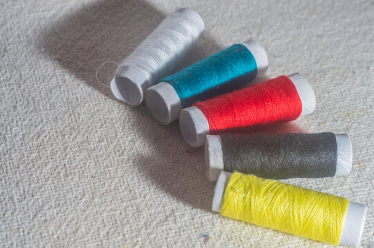 Coils with colorful sewing threads with tablecloth in the background, sewing concept, copy space in parts of the image