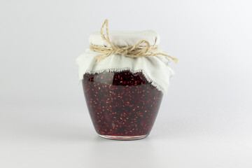 Raspberry jam in glass jar isolated on white background.