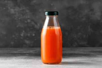 Carrot juice in glass bottle. Freshly squeezed juice on dark background. Mock up, copy space