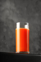 Juice of carrot in glass. Freshly squeezed juice on dark background. For packaging and menu