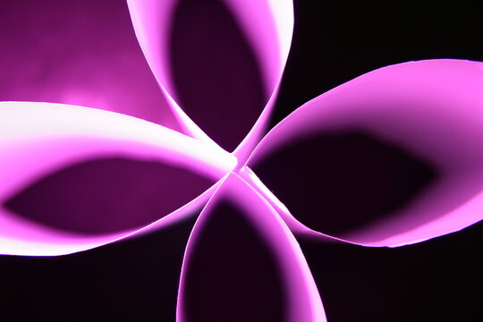 Flor de papel blanco para impresoras con luz de color violeta produce un hermoso dise&ntilde;o gr&agrave;fico con p&egrave;talos en cruz con fondo negro.