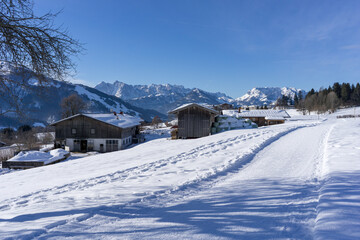 old bavarian farmer houses in the snow surrounded by high mountains in the winter