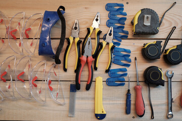 Top view background of tools and safety goggles on wooden table in carpentry workshop