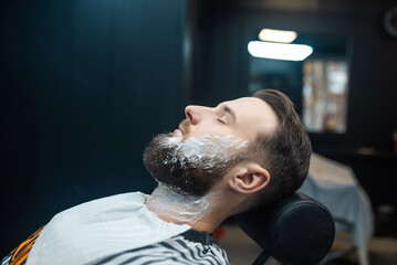Man with shaving foam on his face in a barbershop