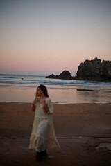 Fototapeta na wymiar young girl enjoying the sunset on the beach in a long dress
