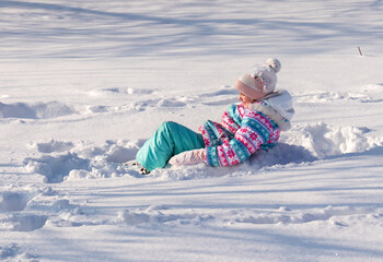 little happy cheerful girl 7-8 years old, playing in a winter snowy park, a child on winter holidays
