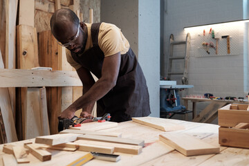 Portrait of mature black man building wooden furniture in carpentry workshop, copy space