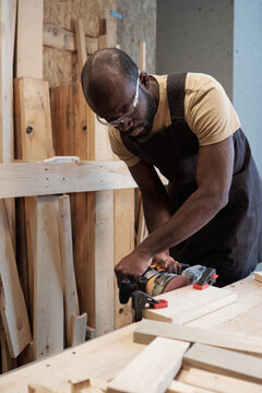 Vertical Portrait Of African-American Man Building Wooden Furniture While Working In Carpentry Shop