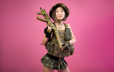 sexy Asian woman in military clothes with an automatic rifle in her hands while serving in the army