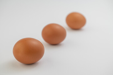 Three brown eggs in a line over white background