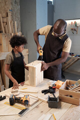 Vertical portrait of African-American father and son working in carpentry workshop together
