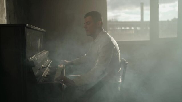 Cinematic slow motion with smoke.
Composer man play on the old piano. Keyboards. Performance on the concert. Musician plays. Soft focused.