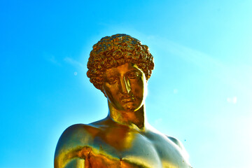 ancient golden statue of a man's faces close-up against the blue sky	