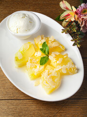 Plate with grilled pineapple slices and vanilla ice cream on wood background. Fruit yellow dessert.