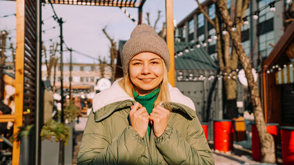 Obraz na płótnie Canvas Beautiful blonde woman looks with a smile while standing outdoors. Perfect weather for hanging out with friends. Urban art space with street food
