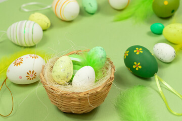 Easter nest with eggs and feathers on a green background close-up. Minimal concept.