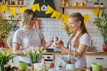 Mom and daughter knock with eggs by checking the strength during Easter