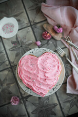 Heart cake with pink cream and confectionery toppings. Desserts and sweets for a romantic holiday