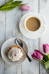 Tulips and a sweet dessert with a cup of coffee on grey wooden table,flat lay. Morning romantic breakfast.