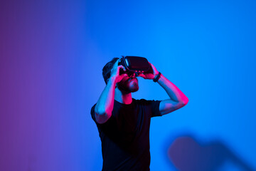 Metaverse and virtual reality concept. European bearded man in vr glasses exploring a virtual world while using a virtual reality headset.