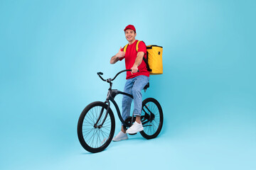 Fototapeta premium Cheerful Male Courier With Bike Gesturing Thumbs Up, Blue Background