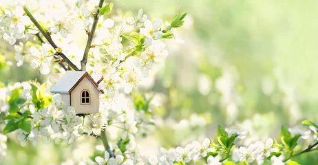 Tuinposter wit stuk speelgoed huis en kersenbloemen, de lente abstracte natuurlijke achtergrond. concept van hypotheek, bouw, verhuur, familie en eigendom. eco-huis. lente seizoen. ruimte kopiëren © Ju_see