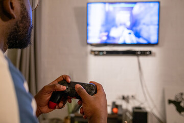 Close-up of African man pushing buttons on console while playing video game in the room at home