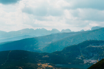 Obraz premium Mountain range with nestled lake clouds and mist covering forests