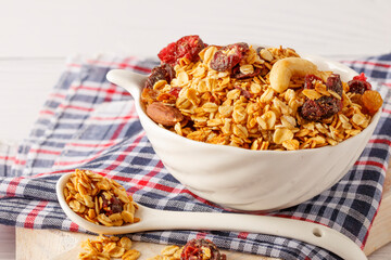 Granola bowl with raisins, nuts and fresh berries. Homemade crunchy granola on grey concrete background, top view
