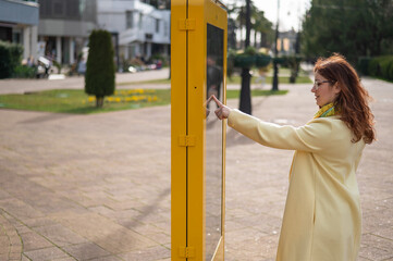 Caucasian woman using touch information board outdoors. 