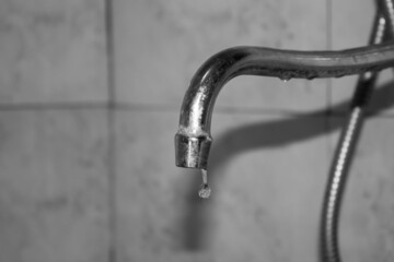 A drop of water from a tap black and white. Old dirty water faucet.