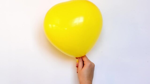 Yellow balloon in shape of heart inflating and deflating slowly video, symbol of love