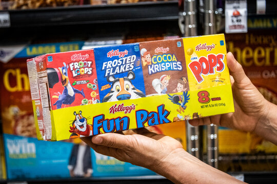 Sacramento, CA/USA 08/25/2021 Shopper hand holding a package of assorted kellogg's brand breakfast cereals small boxes for sale in a supermarket aisle