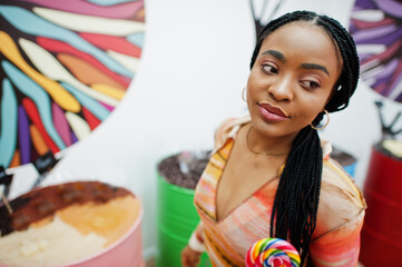 African american millennial lady at candy shop with lolipops.