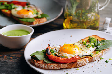 delicious and appetizing bruschetta with fried eggs and herbs for breakfast