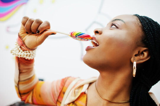 African american millennial lady at candy shop with lolipops.