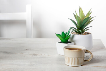 Office desk wood table of the business work place, artificial plants and coffee cup with copy space on grey wooden table.