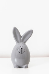 Mock up white frame with modern ceramic easter grey bunny decor on a shelf. White color scheme.
