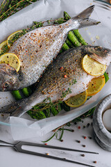 the concept of a delicious dinner for two from dorado. raw baked dorado fish with asparagus and lemon in spices