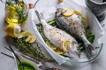 the concept of a delicious dinner for two from dorado. raw baked dorado fish with asparagus and lemon in spices