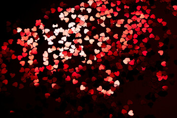 Fototapeta na wymiar red festive confetti in the shape of a heart on a black background