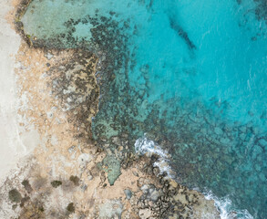 Drone aerial of rocky sea coast with transparent turquoise water. Seascape top view